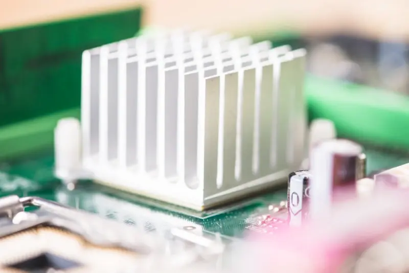 PCB Thermal Design: aluminum heatsink with vertical fins mounted on a PCB, showing passive cooling and component clearance.